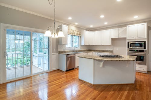 Free Bright modern kitchen featuring marble island and wooden flooring, ideal for family spaces. Stock Photo