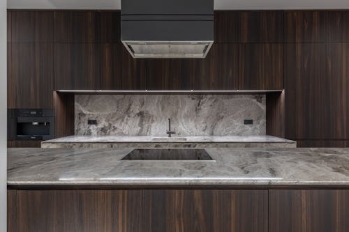 Free Sleek modern kitchen interior featuring marble countertops and dark wood cabinets. Stock Photo